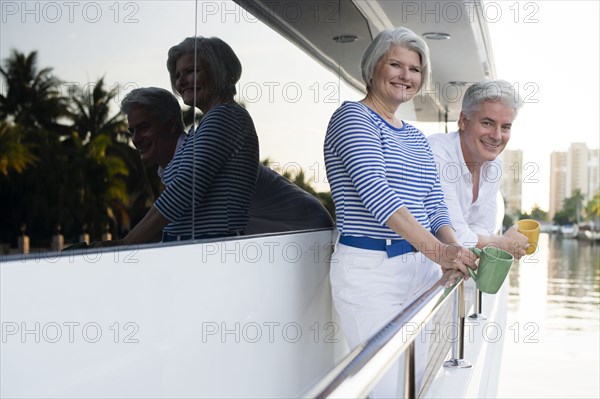 Older Caucasian couple having coffee on boat deck