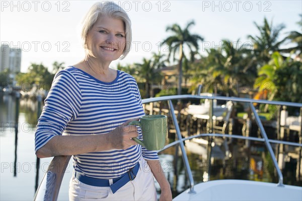 Older Caucasian woman having coffee on boat deck