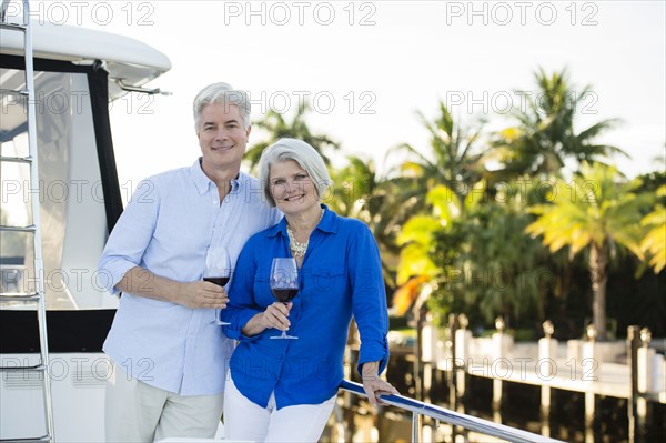 Older Caucasian couple having wine on boat deck