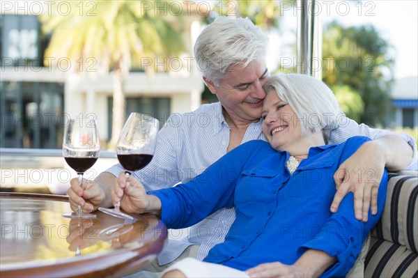 Older Caucasian couple having wine together on boat
