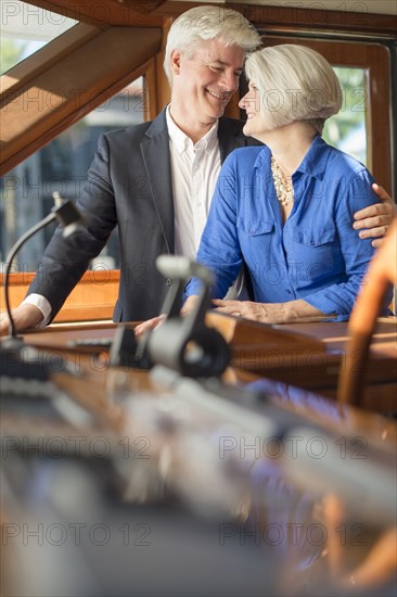 Older Caucasian couple hugging on yacht