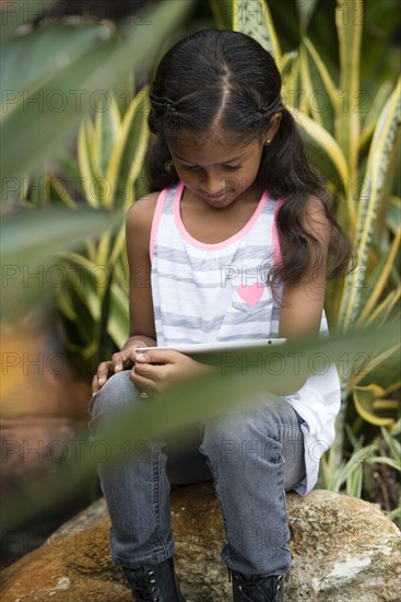 Mixed race girl using digital tablet outdoors