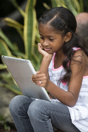 Mixed race girl using digital tablet outdoors