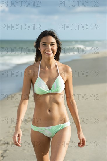 Hispanic woman walking on beach