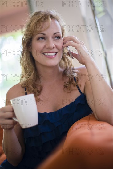 Caucasian woman drinking coffee and talking on cell phone