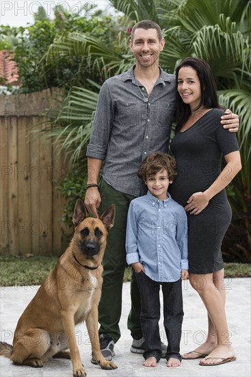 Family smiling together with dog outdoors