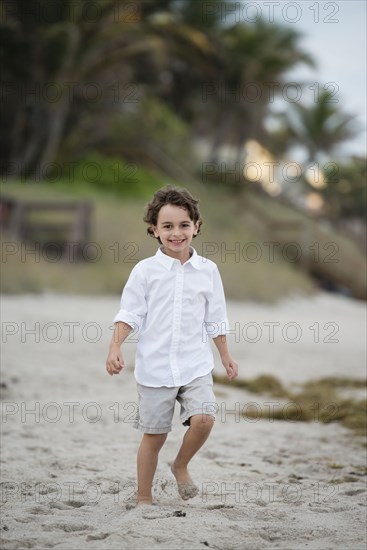 Hispanic boy walking on beach