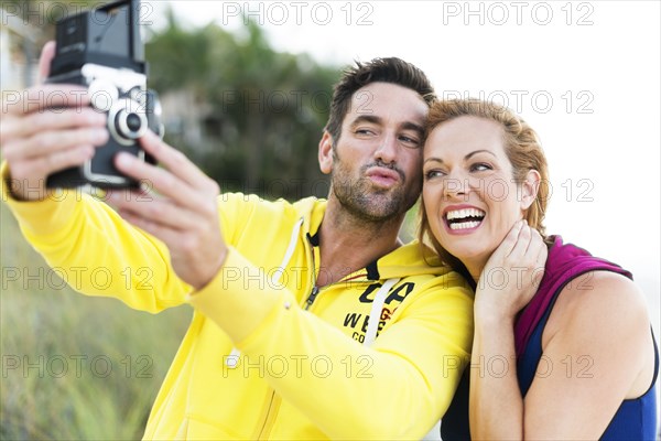 Caucasian couple taking self-portrait with vintage camera