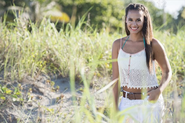 Mixed race woman smiling in tall grass