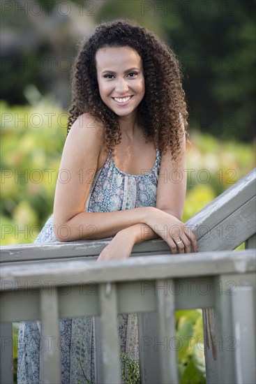 Mixed race woman leaning on wooden banister