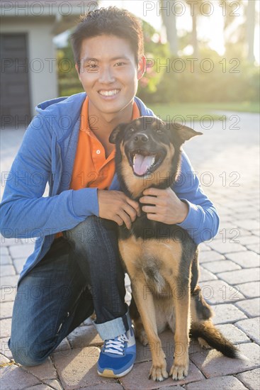 Korean man hugging dog in driveway