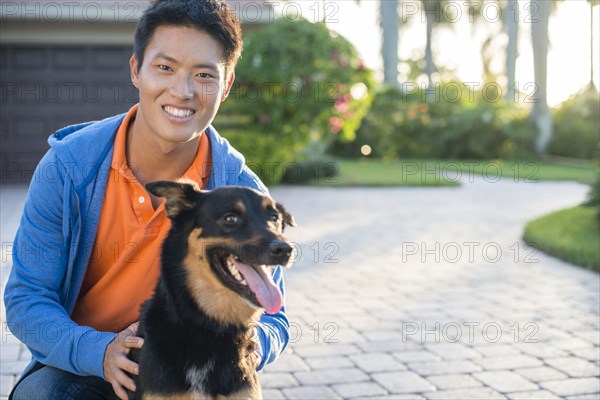 Korean man holding dog in driveway