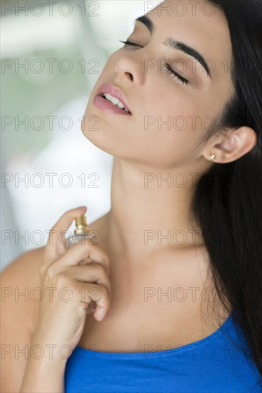 Hispanic woman spraying perfume