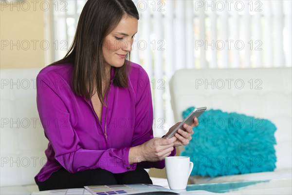 Caucasian businesswoman using cell phone on sofa