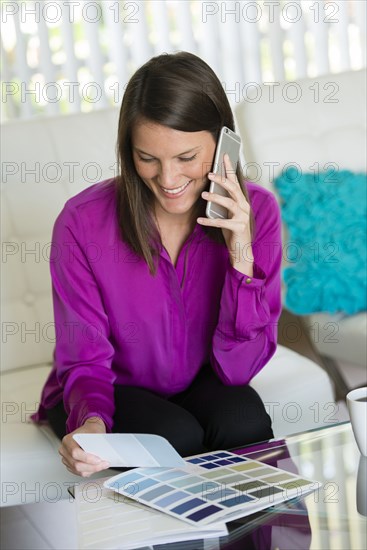 Caucasian businesswoman talking on cell phone and examining color swatches