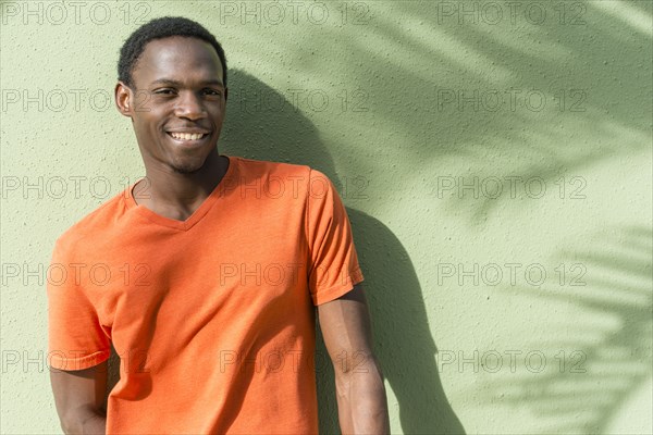 Black man standing under palm tree shadow on wall