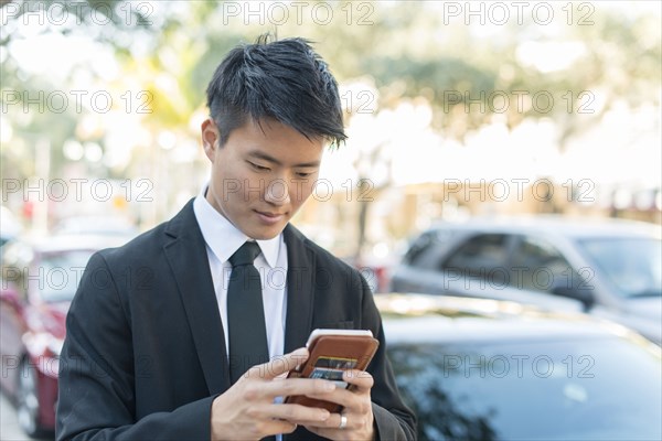 Korean businessman using cell phone outdoors