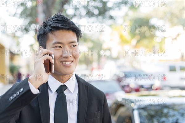 Korean businessman talking on cell phone outdoors