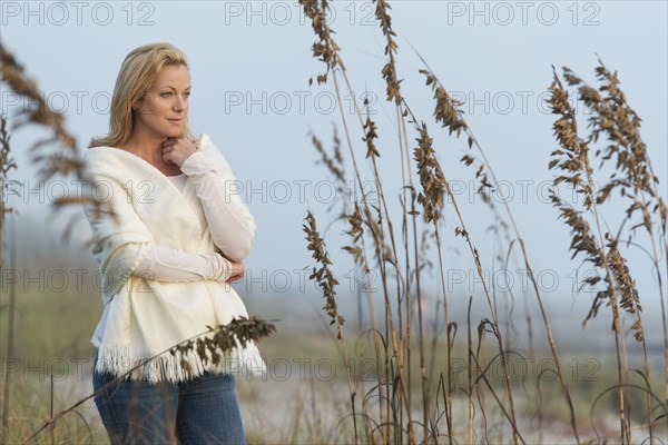 Caucasian woman standing in tall grass on beach