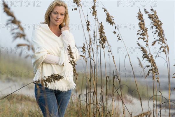 Caucasian woman standing in tall grass on beach