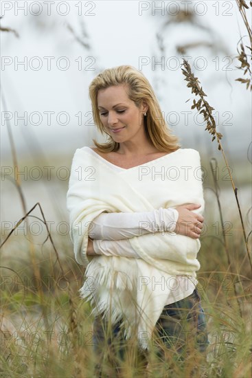 Caucasian woman standing in tall grass on beach