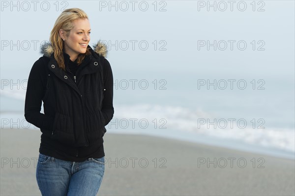 Caucasian woman wearing jacket on beach