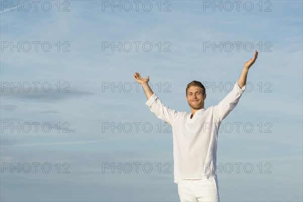 Caucasian man standing with arms raised outdoors