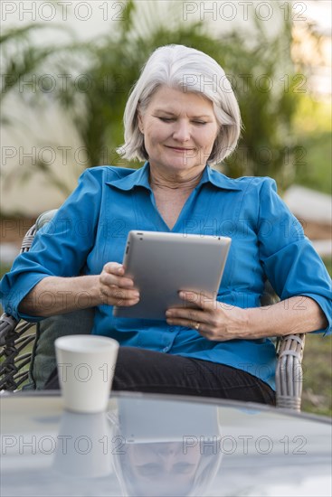 Caucasian older woman using digital tablet in backyard