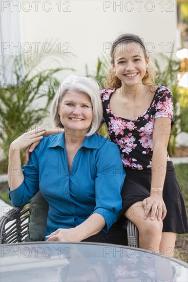 Older grandmother and granddaughter smiling in backyard