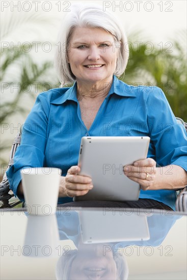 Caucasian older woman using digital tablet in backyard