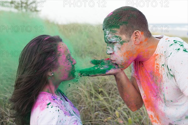 Caucasian man blowing paint powder on girlfriend