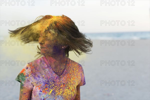 Caucasian woman splattered with paint powder shaking hair