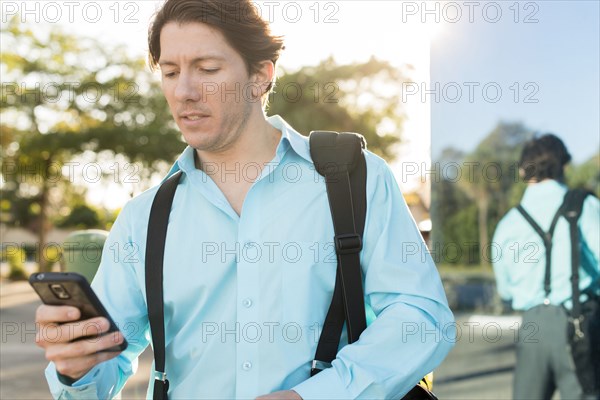 Hispanic businessman texting on cell phone outdoors