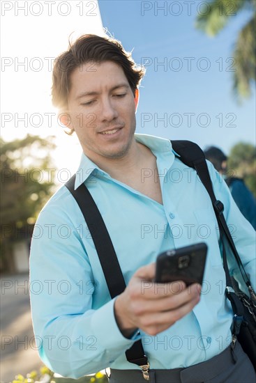 Hispanic businessman texting on cell phone outdoors