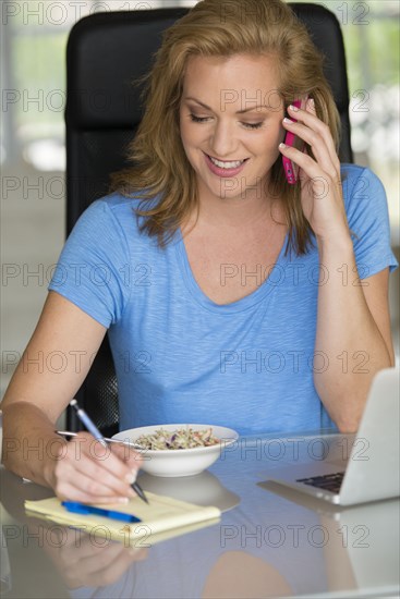 Caucasian businesswoman talking on cell phone at breakfast