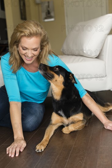 Caucasian woman playing with dog in bedroom