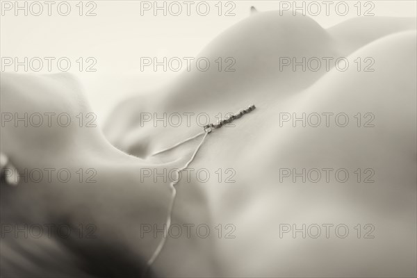 Close up of nude Caucasian woman wearing necklace