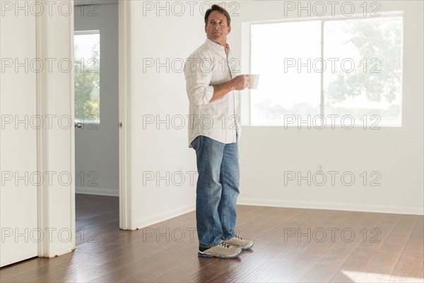 Caucasian man drinking cup of coffee in empty room