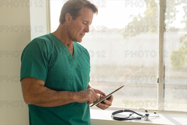 Caucasian nurse using digital tablet near window