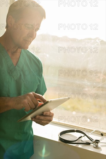 Caucasian nurse using digital tablet near window