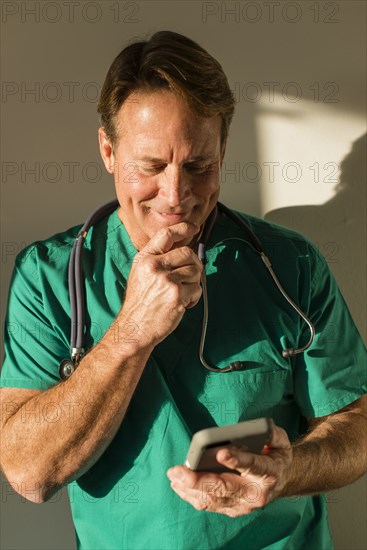 Caucasian nurse using cell phone casting shadow on wall