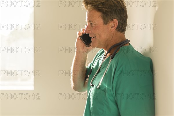 Caucasian nurse talking on cell phone near window