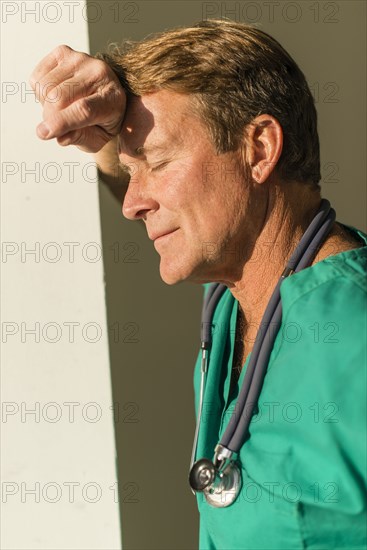 Stressed Caucasian nurse leaning on wall