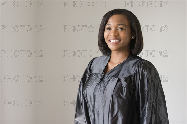 Mixed race graduate smiling in graduation robe