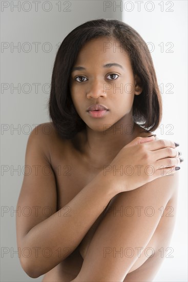 Nude mixed race woman covering bare chest