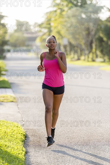 Mixed race woman jogging on suburban sidewalk