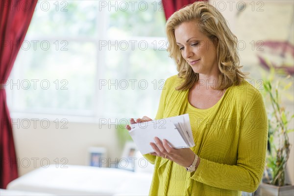 Caucasian woman sorting mail in living room