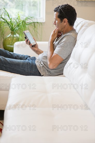 Hispanic man using cell phone on sofa