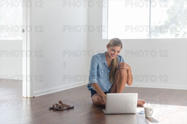 Caucasian woman using laptop in empty room