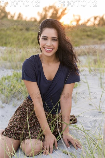 Hispanic woman sitting on sand dunes